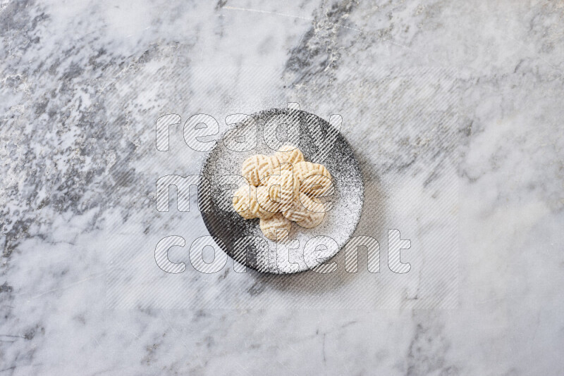 كحك في صحن فخار أسود على خلفية رخام رمادي