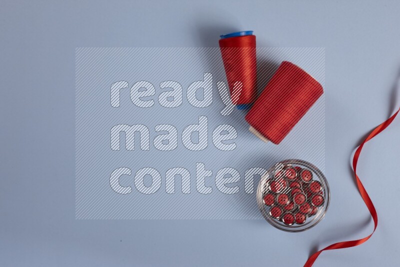 مجموعة من أدوات الخياطة والتفصيل حمراء اللون على خلفية زرقاء