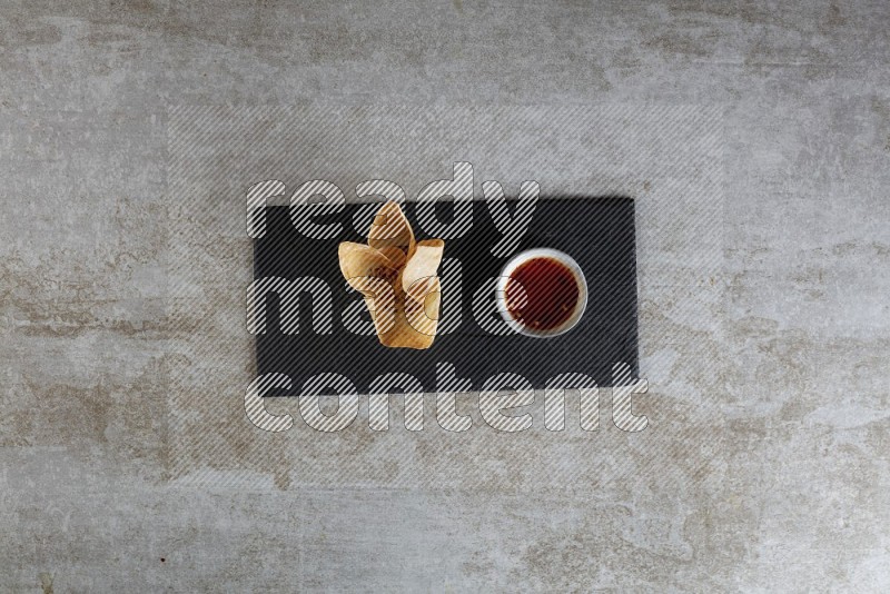 wonton cups with soy sauce ramkin on rectangle slate on grey textured counter top