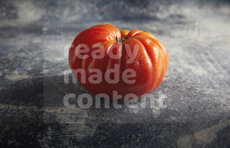 45 degree single heirloom tomato on a textured rustic blue background