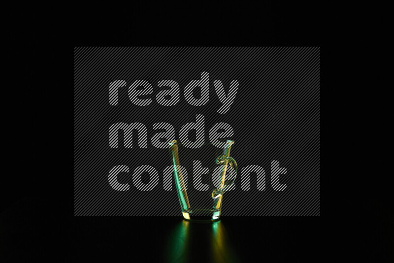 Glassware with rim light in green and yellow against black background