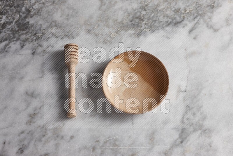 Multicolored pottery plate with wooden honey dipper on the side on grey marble background