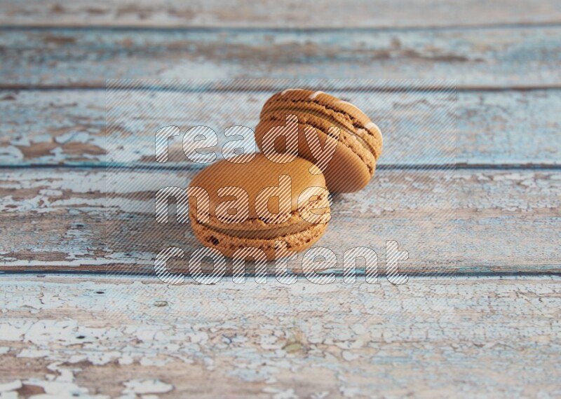 45º Shot of of two assorted Brown Irish Cream, and Brown Maple Taffy macarons  on light blue background