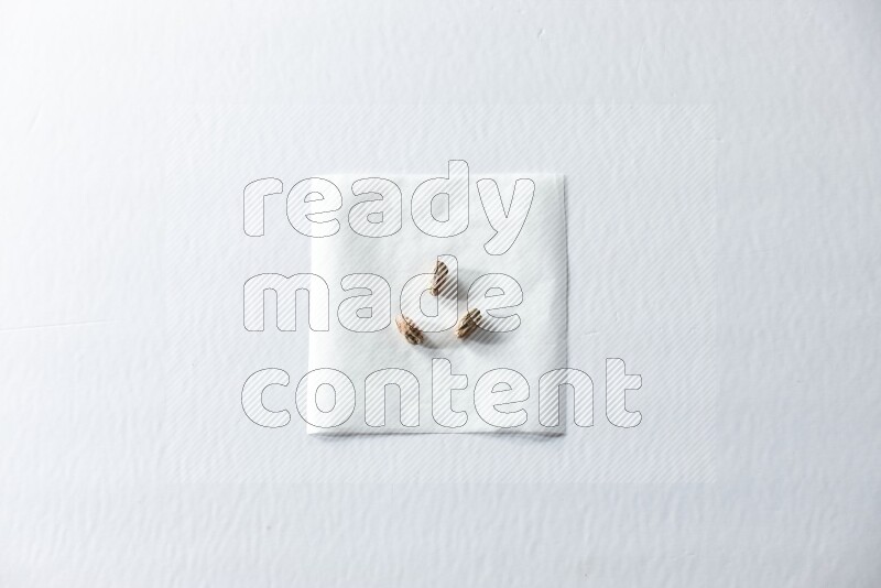 3 حبات من الفستق المقشر على قطعة من الورق على خلفية بيضاء