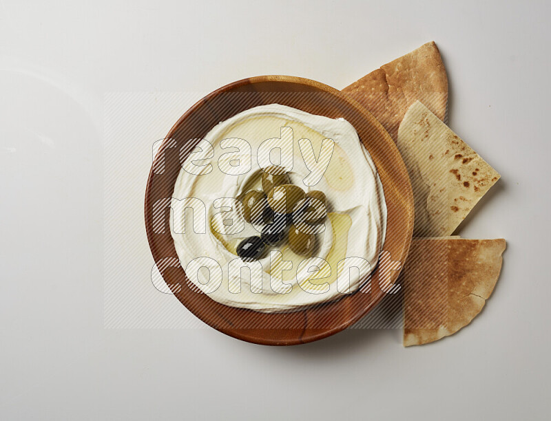 Lebnah garnished with whole olives in a wooden plate on a white background