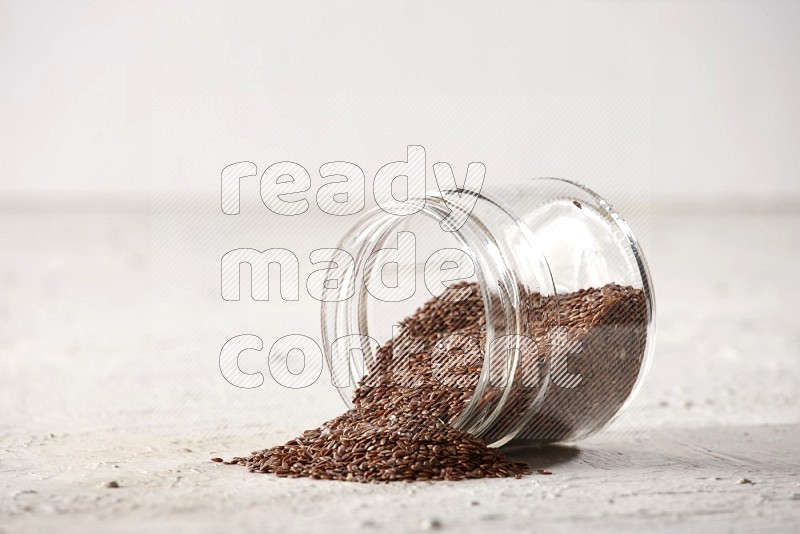 A glass jar full of flax flipped and flax spreaded out on a textured white flooring in different angles