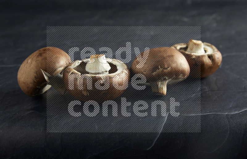 45 degre cremini  mushrooms on a textured black slate background