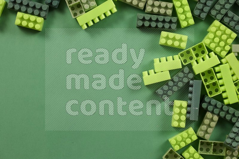 Green plastic building blocks on green background in top view (kids toys)