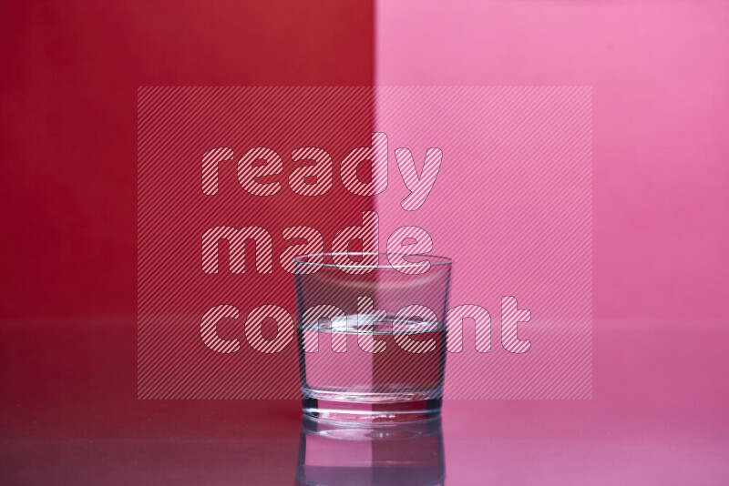 The image features a clear glassware filled with water, set against red and pink background