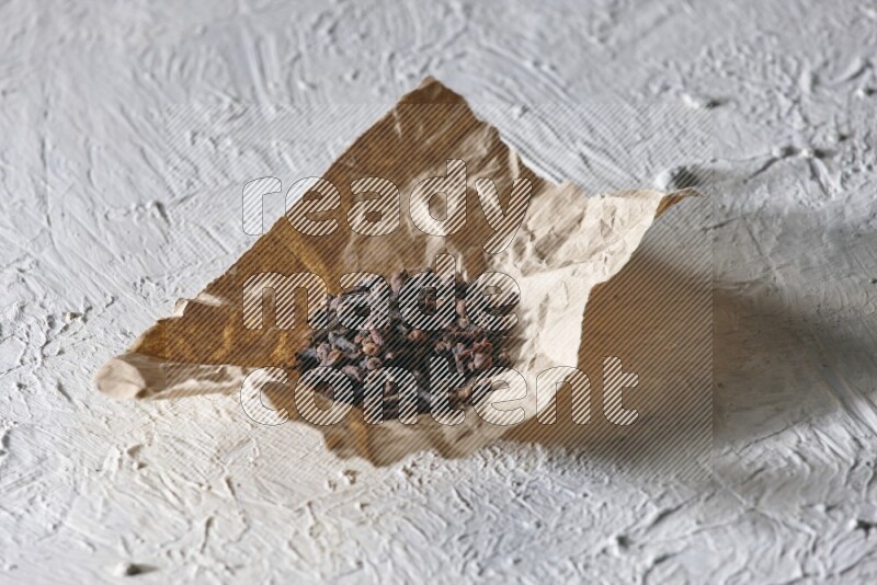 Cloves on crumpled piece of paper on a textured white flooring