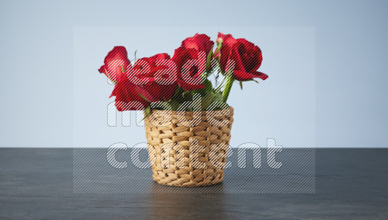باقة من الورود الحمراء موضوعة في سلة خوص على خلفية من الرخام الأسود