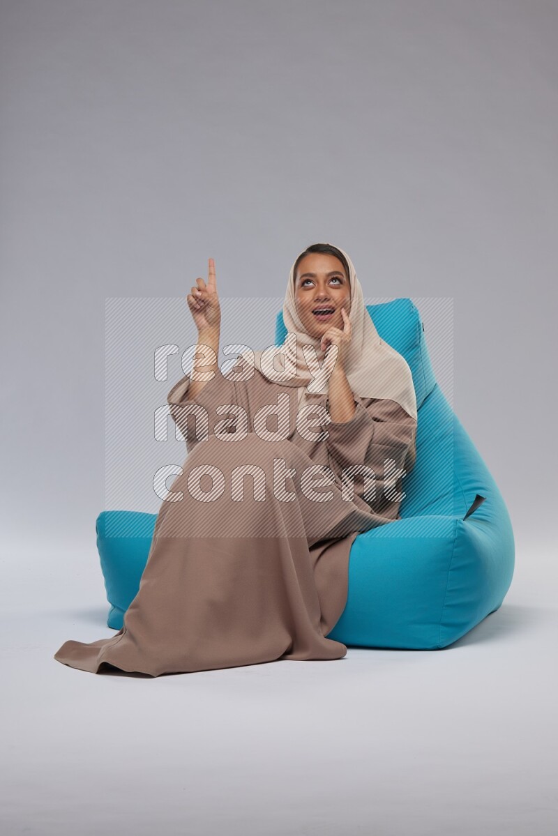 A woman sitting on a blue beanbag and interacting with the camera