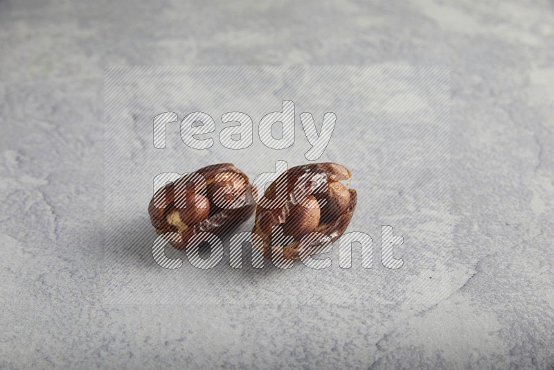 Two hazulnut stuffed dates on light grey background