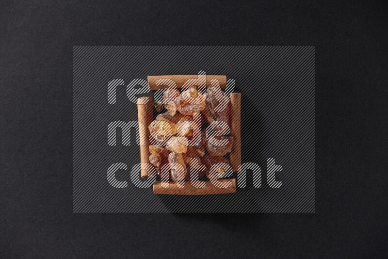 A single square of cinnamon sticks full of Arabic gum on black flooring