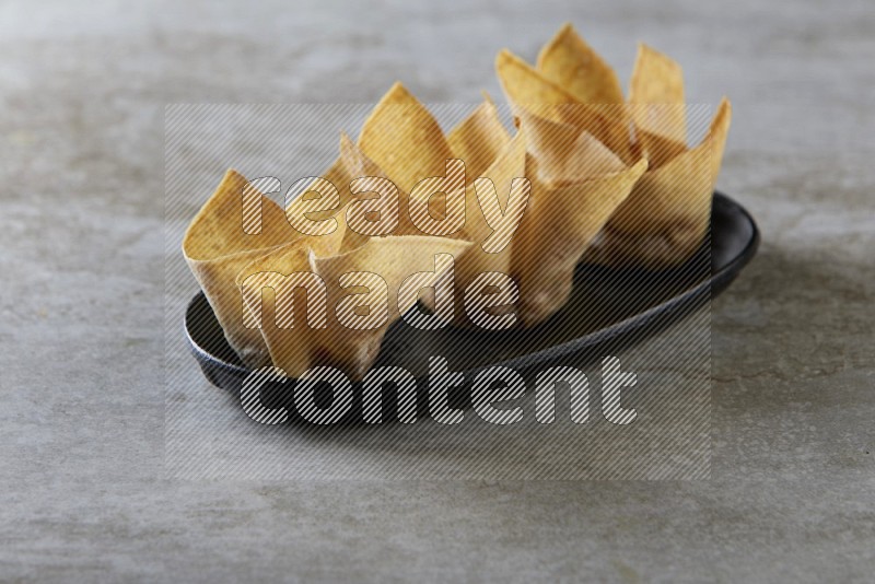 wonton cups on oval black ceramic plate on grey textured counter top