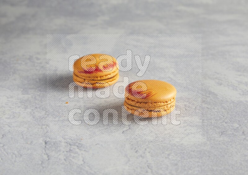 45º Shot of two orange Exotic macarons on white  marble background