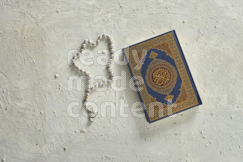 Quran with a prayer beads on white background