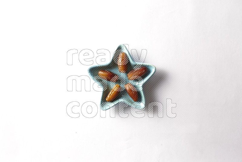 Libyan dates in a star shaped pottery plate on white background