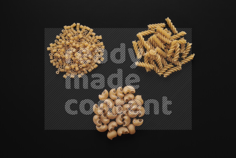 Different pasta types in bunches on black background