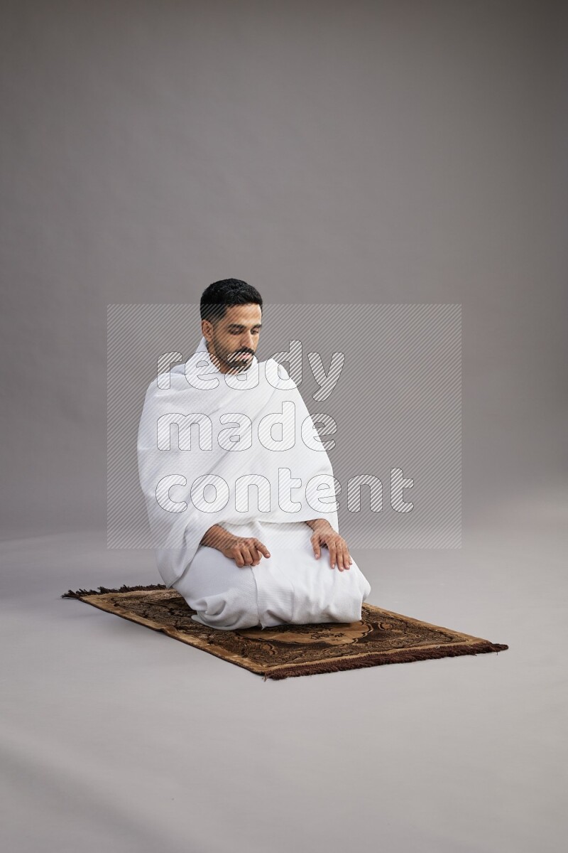 A man wearing Ehram praying on gray background