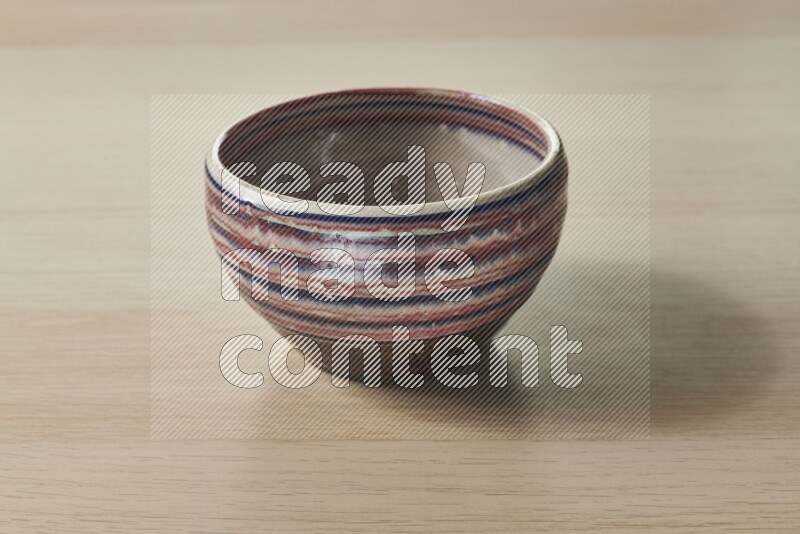 A multicolored pottery bowl on light wooden background