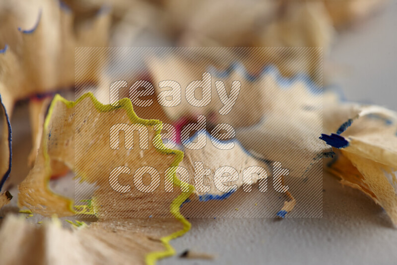A close-up showing a small pile of pencil shavings with varied color edges on grey background