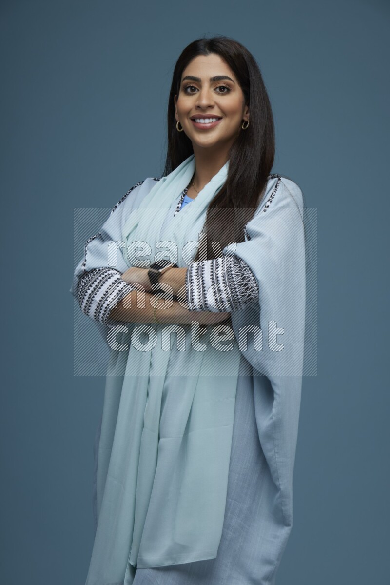 A woman posing in a blue background wearing blue Abaya no Hijab