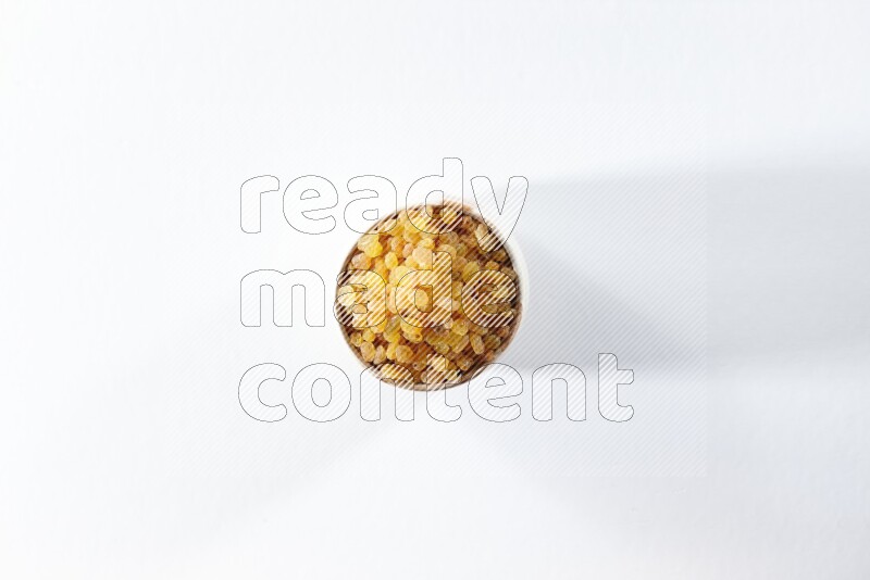 A beige ceramic bowl full of raisins on a white background in different angles