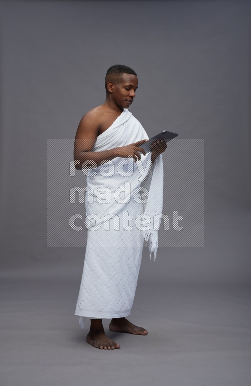 A man wearing Ehram Standing working on tablet on gray background