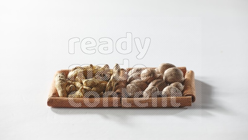 مربعان من أعواد القرفة ممتلئان بأصابع الكركم  وجوزة الطيب علي خلفية بيضاء