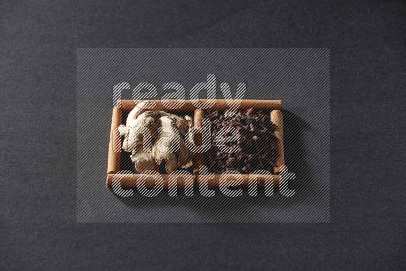 2 squares of cinnamon sticks full of cloves and dried ginger on black flooring