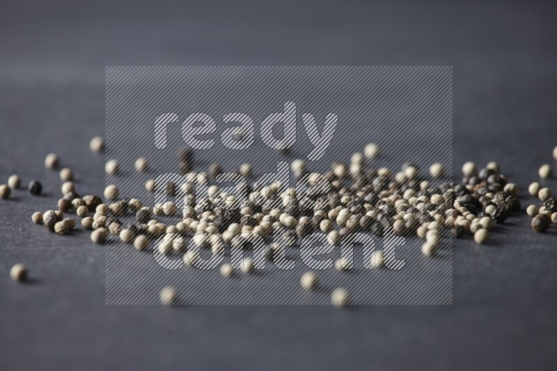 حبوب الفلفل المختلطة السوداء والبيضاء على أرضية سوداء