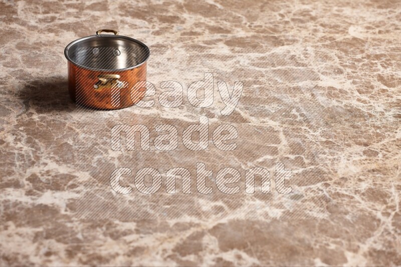 A small copper pot on beige marble background