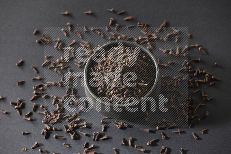 وعاء فخاري أسود ممتلئ بحبوب القرنفل علي خلفية سوداء