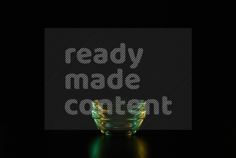 Glassware with rim light in green and yellow against black background