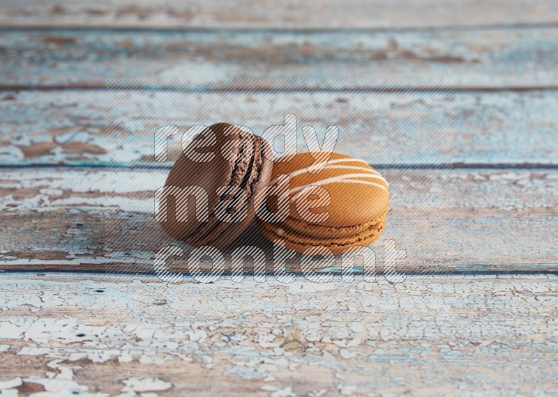 45º Shot of of two assorted Brown Irish Cream, and Brown Dark Chocolate macarons on light blue background