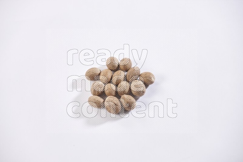 A bunch of whole nutmeg seeds on a white flooring
