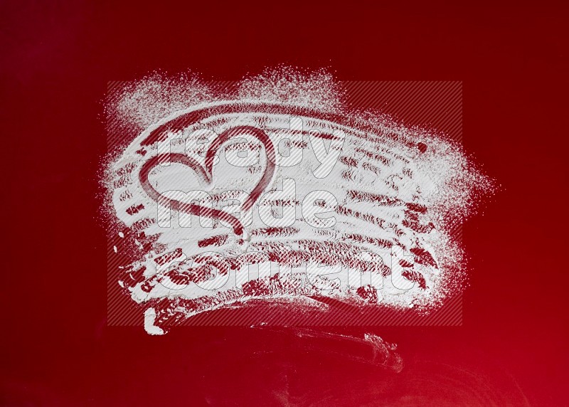 A heart drawn with powder on red background
