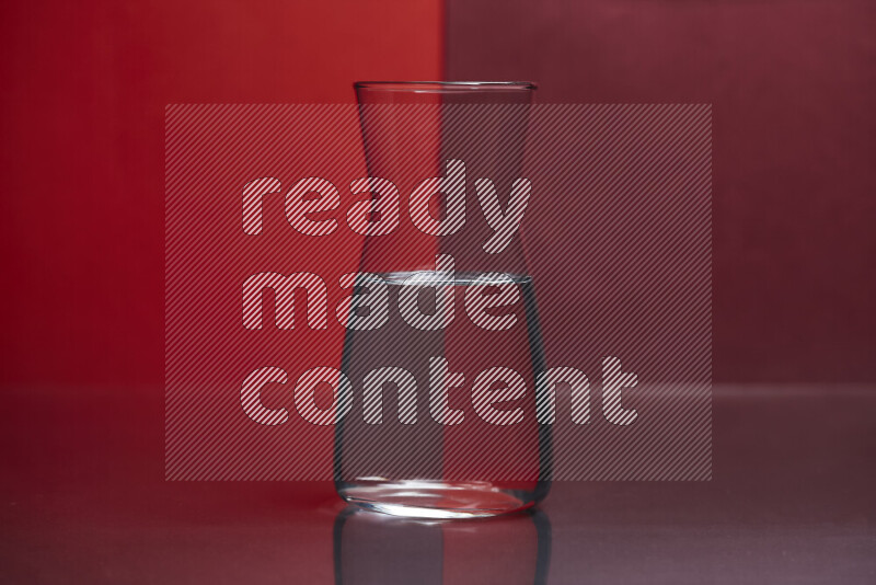 The image features a clear glassware filled with water, set against red and dark red background