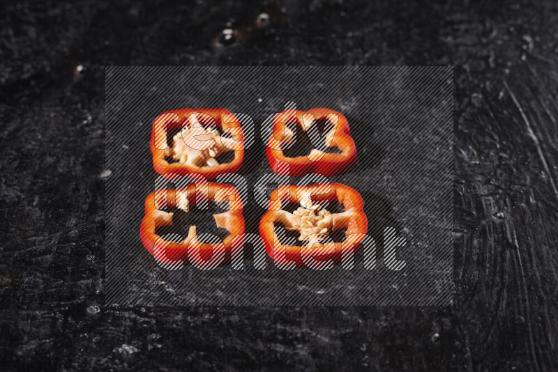 Red bell pepper slices on black background