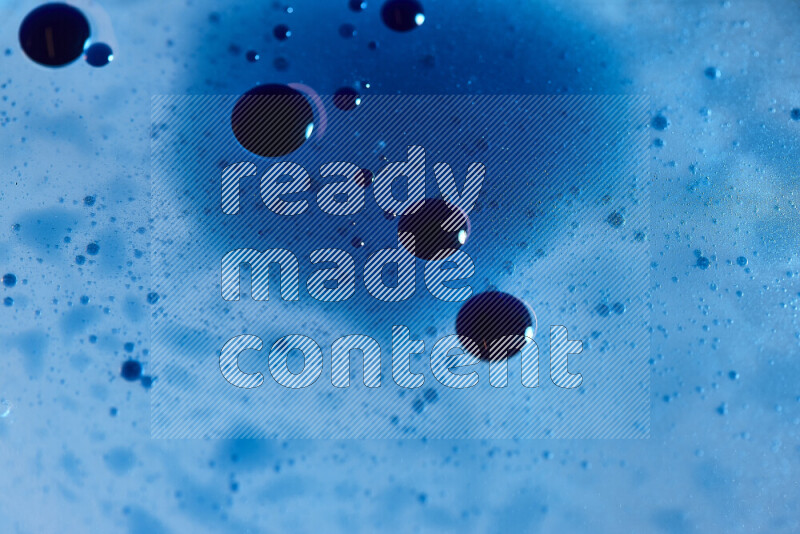 لقطات مقربة لقطرات ألوان مائية زرقاء على سطح الزيت على خلفية زرقاء