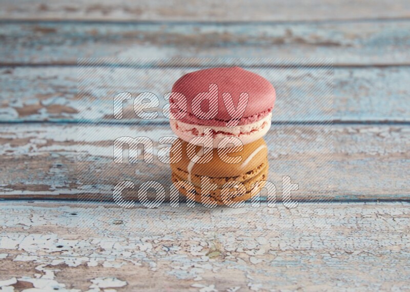 45º Shot of of two assorted Brown Irish Cream, and Pink Litchi Raspberry macarons on light blue background