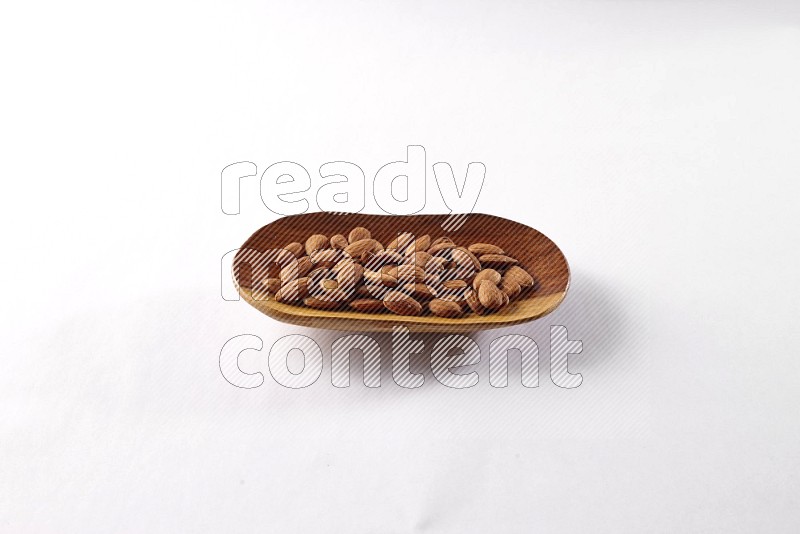 Almonds in a wooden plate on white background
