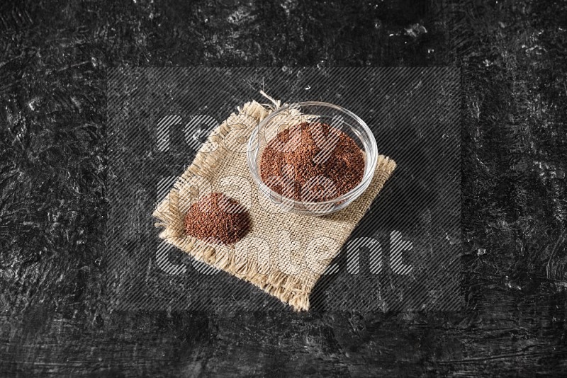A glass bowl full of garden cress and the seeds on burlap fabric on a textured black flooring in different angles