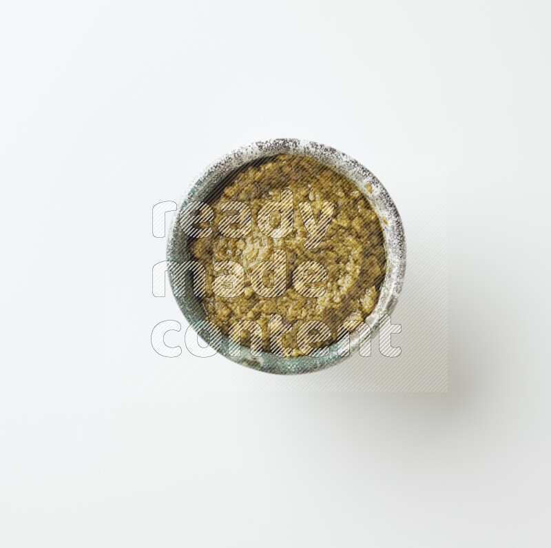 medium multi color pottery round bowl filled with pesto paste on a white counter top