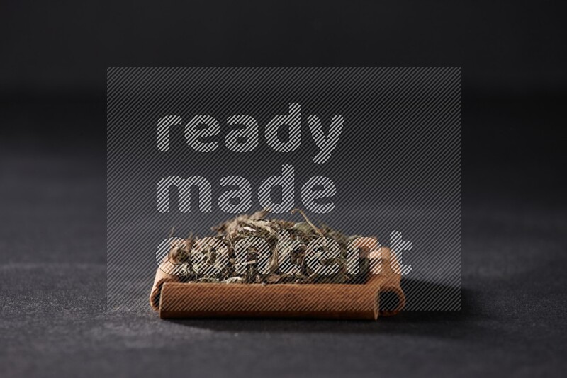 A single square of cinnamon sticks full of dried basil on black flooring