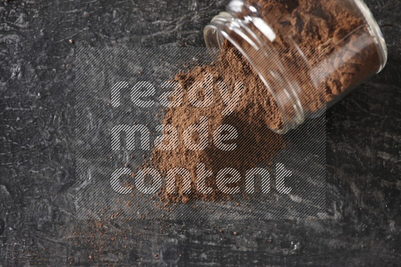 وعاء زجاجي مقلوب ممتلئ ببودرة القرنفل على أرضية سوداء