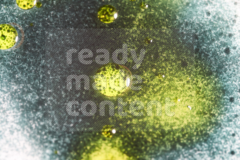 Close-ups of abstract green and yellow watercolor drops on oil Surface on white background