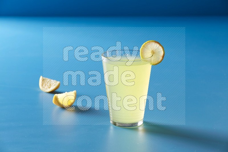 glass of lemon juice with lemon slice  on blue background