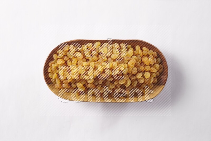 زبيب في صحن خشبي على خلفية بيضاء